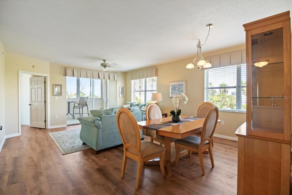 A dining area and living room with wood-look flooring, light walls, and a balcony view — 2625 TERRA CEIA BAY BOULEVARD UNIT 206, PALMETTO, FL