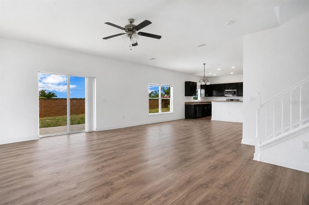 An open-concept living area with wood-look flooring, a ceiling fan, and an adjacent kitchen — 1370 SALISBURY DRIVE, WINTER HAVEN, FL