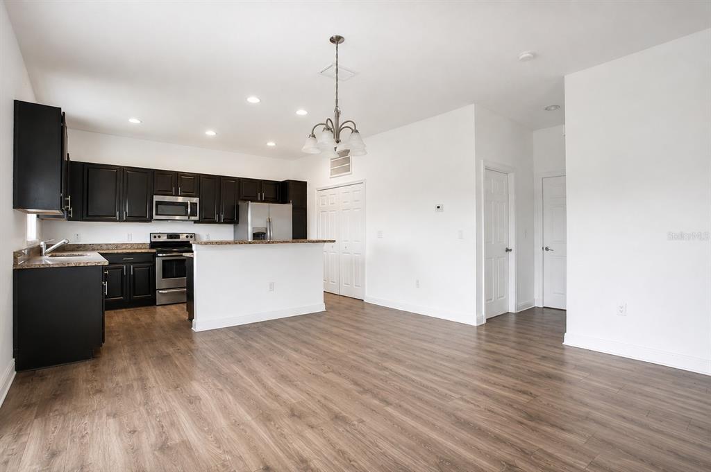 A kitchen with dark cabinets, stainless steel appliances, and a breakfast bar overlooks a living area — 1370 SALISBURY DRIVE, WINTER HAVEN, FL