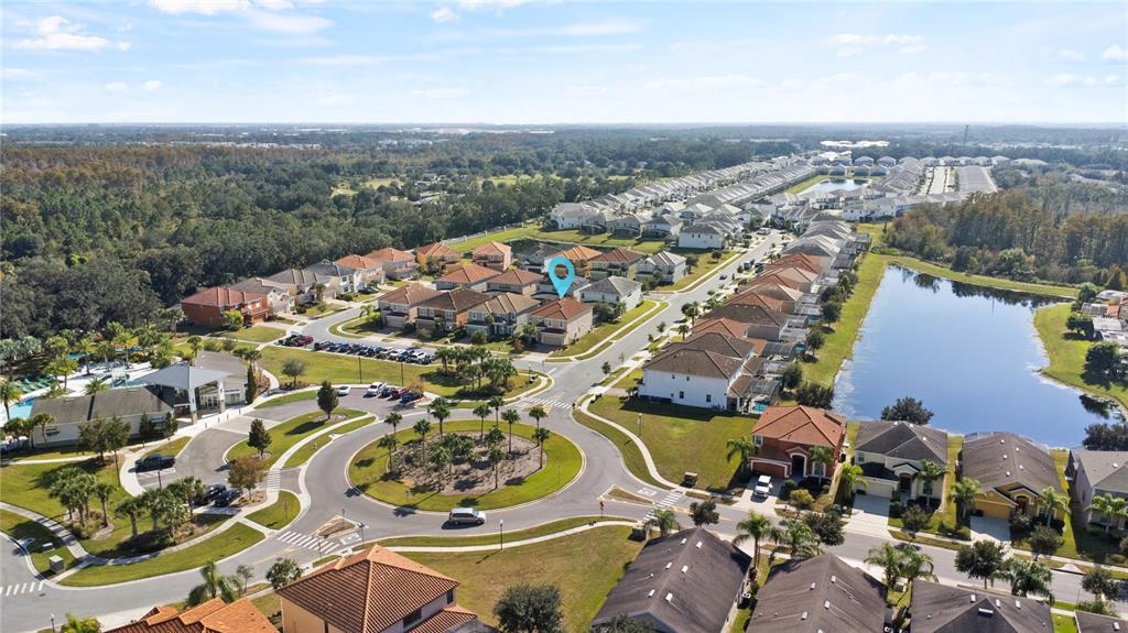 An aerial view shows a residential neighborhood with a roundabout, a lake, and houses — 4414 SHIVA LOOP, KISSIMMEE, FL