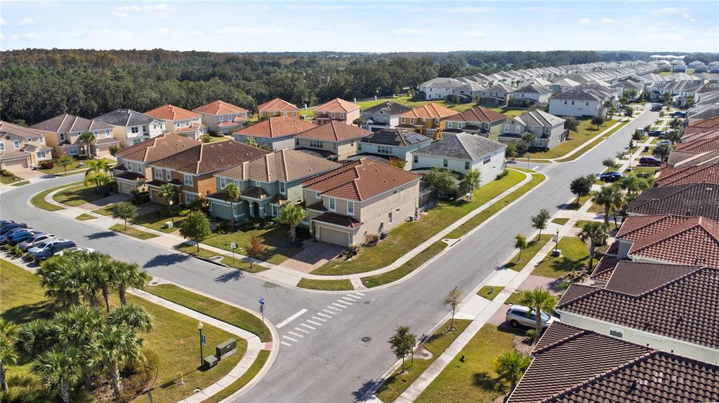 An aerial view shows a suburban neighborhood with houses, paved streets, and palm trees — 4414 SHIVA LOOP, KISSIMMEE, FL