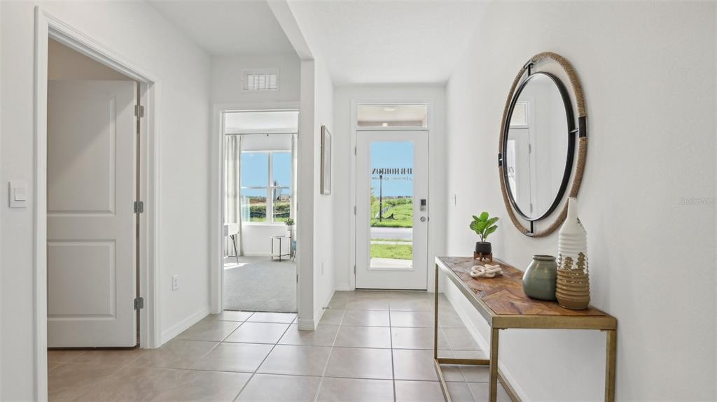 A bright entryway features tile flooring, a console table with a mirror, and two doorways — 1213 12TH STREET SE, RUSKIN, FL