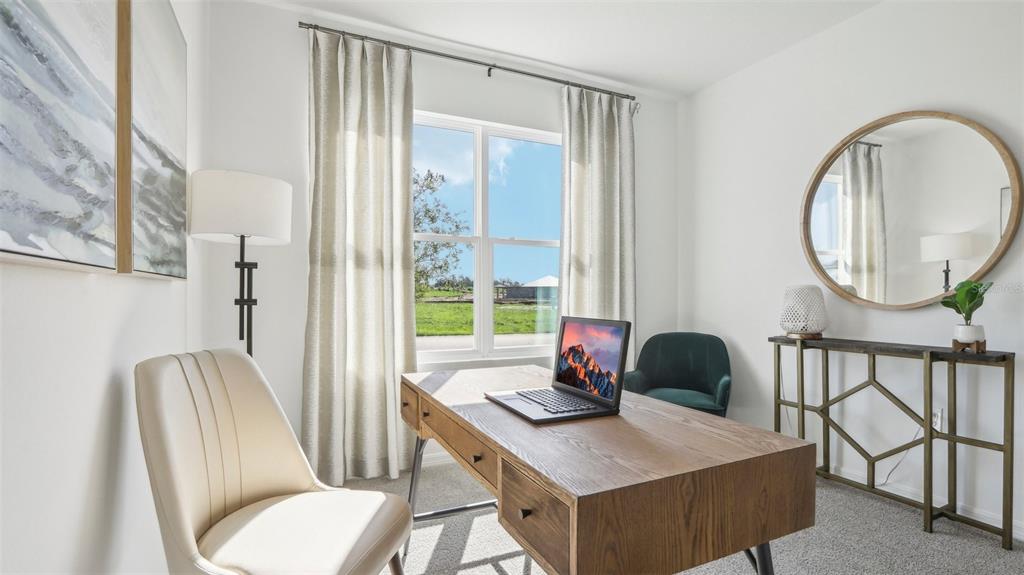 A home office features a wooden desk, a beige chair, and a large round mirror — 1213 12TH STREET SE, RUSKIN, FL