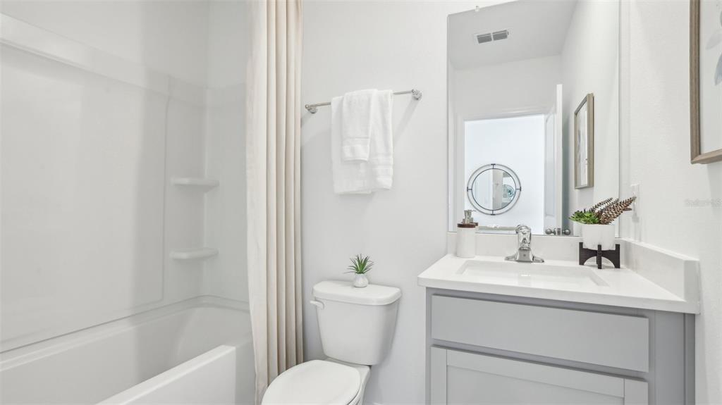 A bathroom features a white vanity, a toilet, and a shower-tub combination with a curtain — 1213 12TH STREET SE, RUSKIN, FL
