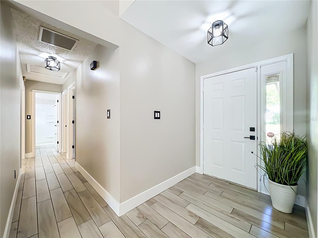 A bright entryway features light wood-look tile flooring, white doors, and two geometric pendant lights — 5915 GROVELINE DRIVE, ORLANDO, FL