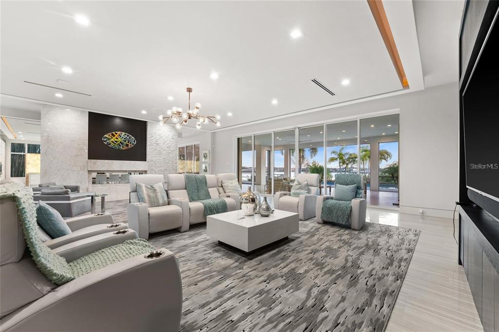 A modern living room features light-colored furniture, a large area rug, and floor-to-ceiling glass doors — 12264 MONTALCINO CIRCLE, WINDERMERE, FL