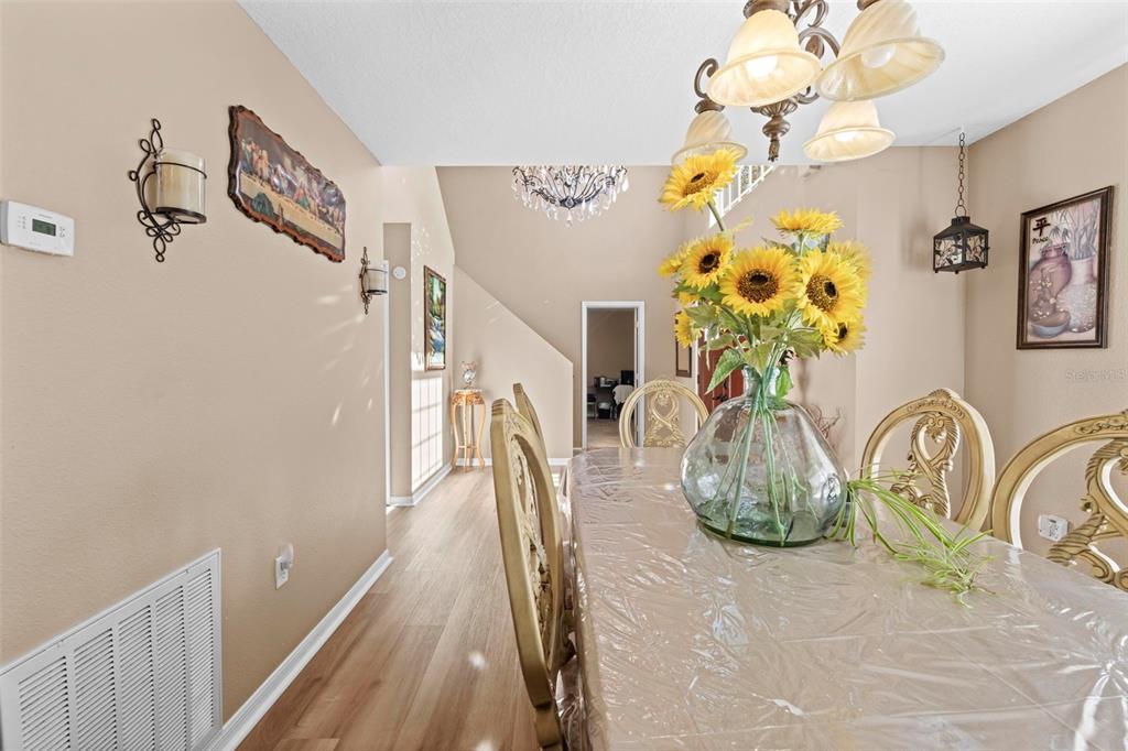 A dining room features a glass-topped table with sunflowers, ornate chairs, and a chandelier — 7319 LAGOON ROAD, SPRING HILL, FL