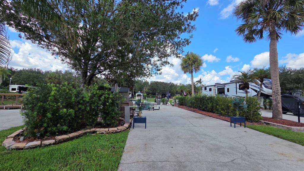 A patio with two chairs and an umbrella sits beside a parked recreational vehicle — 579 WATERWAY DRIVE, RIVER RANCH, FL