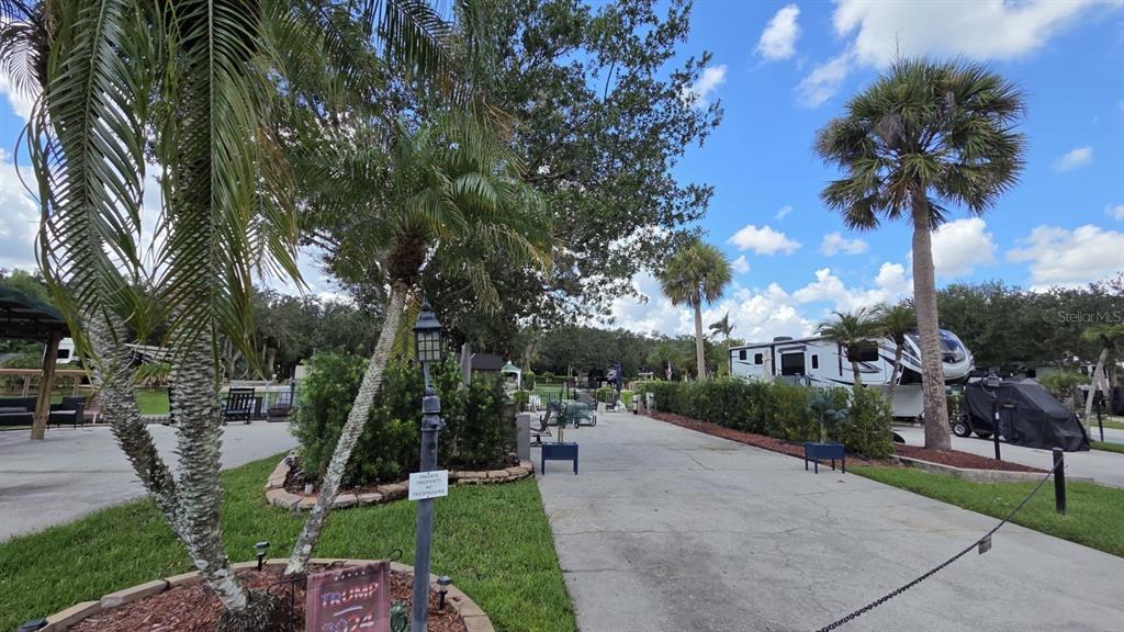 A patio features a white metal picnic table with blue cushions beside a parked RV — 579 WATERWAY DRIVE, RIVER RANCH, FL