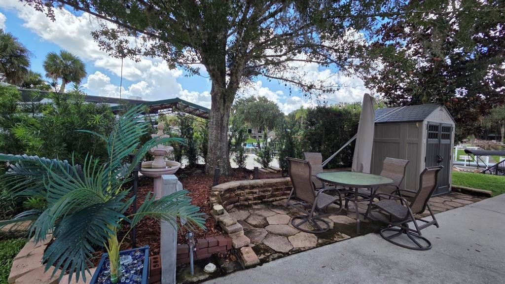 A wooden deck with a boat slip and canopy overlooks a canal lined with trees — 579 WATERWAY DRIVE, RIVER RANCH, FL