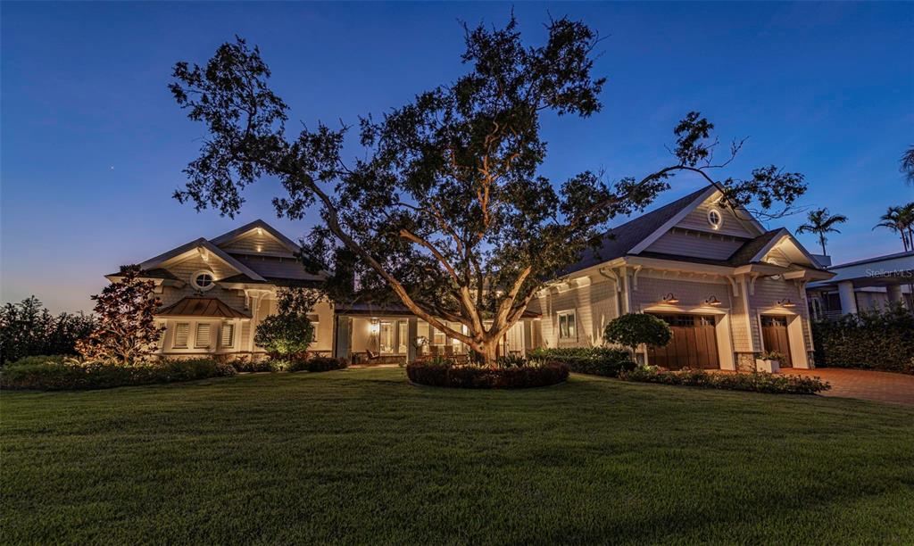 A large, single-story house with a prominent oak tree in the front yard at dusk — 1744 SANTA BARBARA DRIVE, DUNEDIN, FL