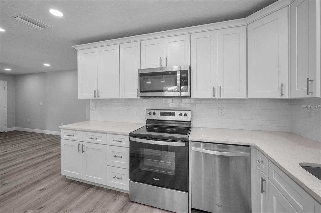 A kitchen features white shaker cabinets, stainless steel appliances, and light-colored countertops with subway tile backsplash — 2307 N 47TH STREET, TAMPA, FL