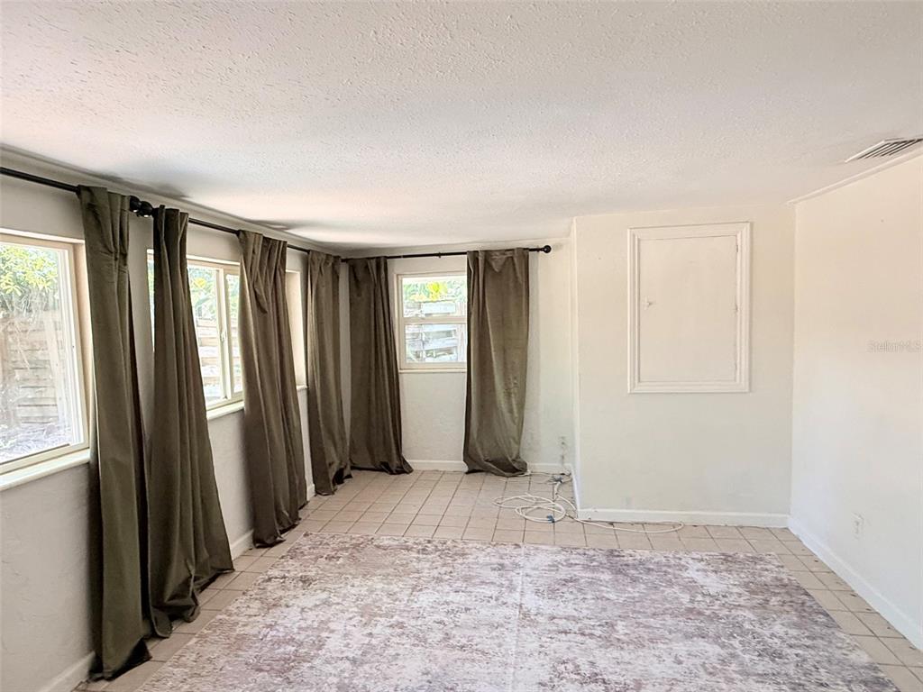 A room with tiled floors, olive green curtains, and a glass door leading outside — 776 27TH AVENUE N UNIT 2, ST PETERSBURG, FL
