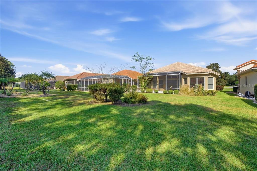 The exterior view shows the back of a house with a screened-in lanai and lawn — 1650 W LAUREL GLEN PATH, HERNANDO, FL