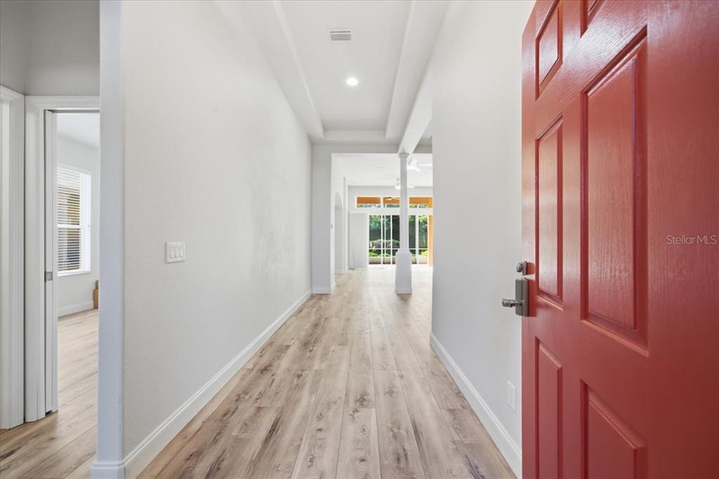 An entryway with light wood-look flooring leads to an open living area with a column — 1650 W LAUREL GLEN PATH, HERNANDO, FL