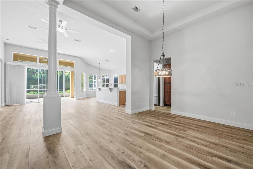 An open-concept living and dining area features light wood-look flooring, a central column, and recessed lighting — 1650 W LAUREL GLEN PATH, HERNANDO, FL