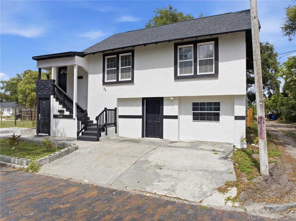 A two-story white house with black trim, an exterior staircase, and a concrete driveway — 1340 13TH AVENUE S, ST PETERSBURG, FL