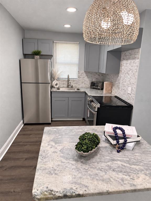 A kitchen with gray cabinets, stainless steel appliances, and a breakfast bar with two stools — 1340 13TH AVENUE S, ST PETERSBURG, FL