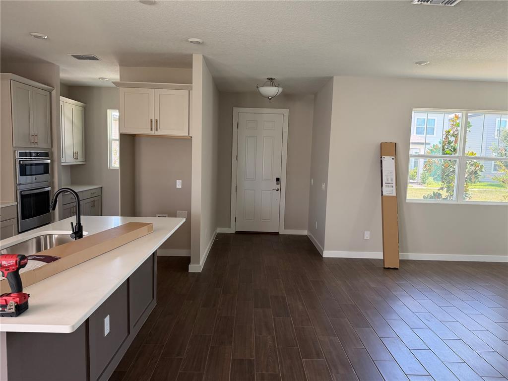 A kitchen with a center island, dark wood-look tile flooring, and an adjacent entryway — 17819 TWISTED MANDARIN ALLEY, WINTER GARDEN, FL