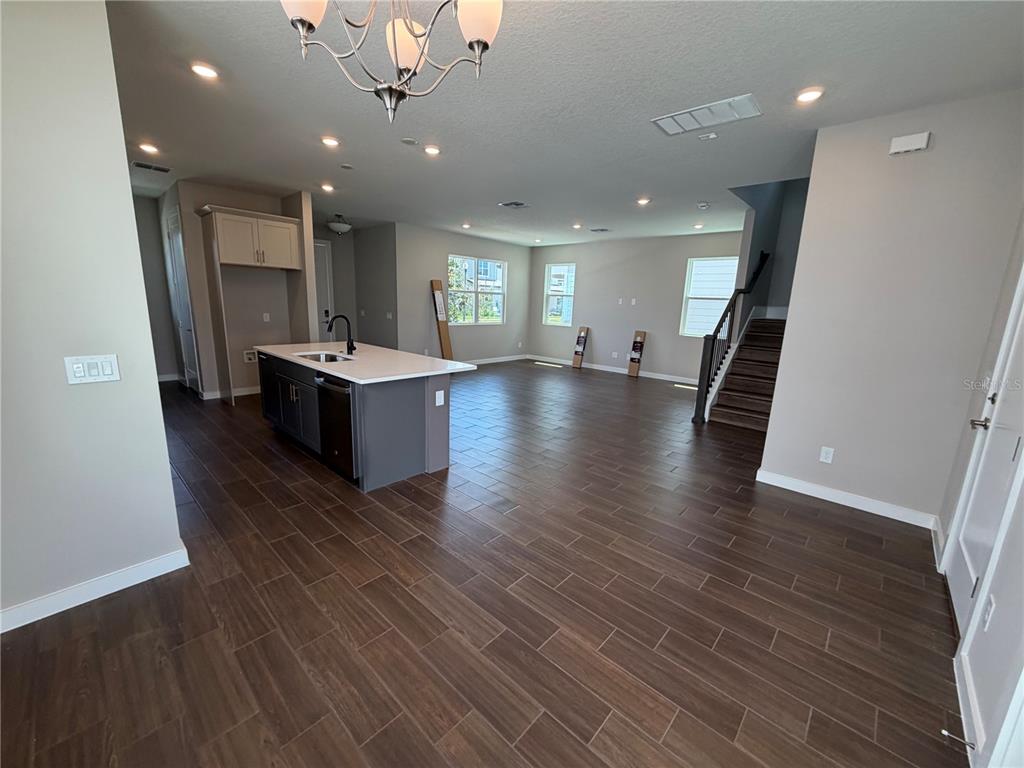 An open-concept kitchen and living area features dark wood-look tile flooring and a center island — 17819 TWISTED MANDARIN ALLEY, WINTER GARDEN, FL