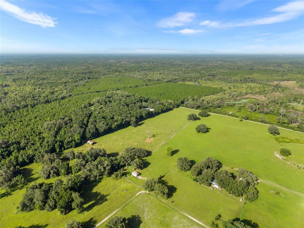 An aerial view shows a large green pasture with scattered trees and several small buildings — 390 SE 30TH AVENUE, TRENTON, FL