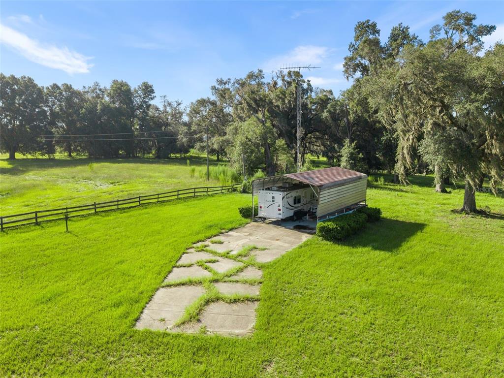 An aerial view shows a camper parked under a metal carport on a grassy lot — 390 SE 30TH AVENUE, TRENTON, FL