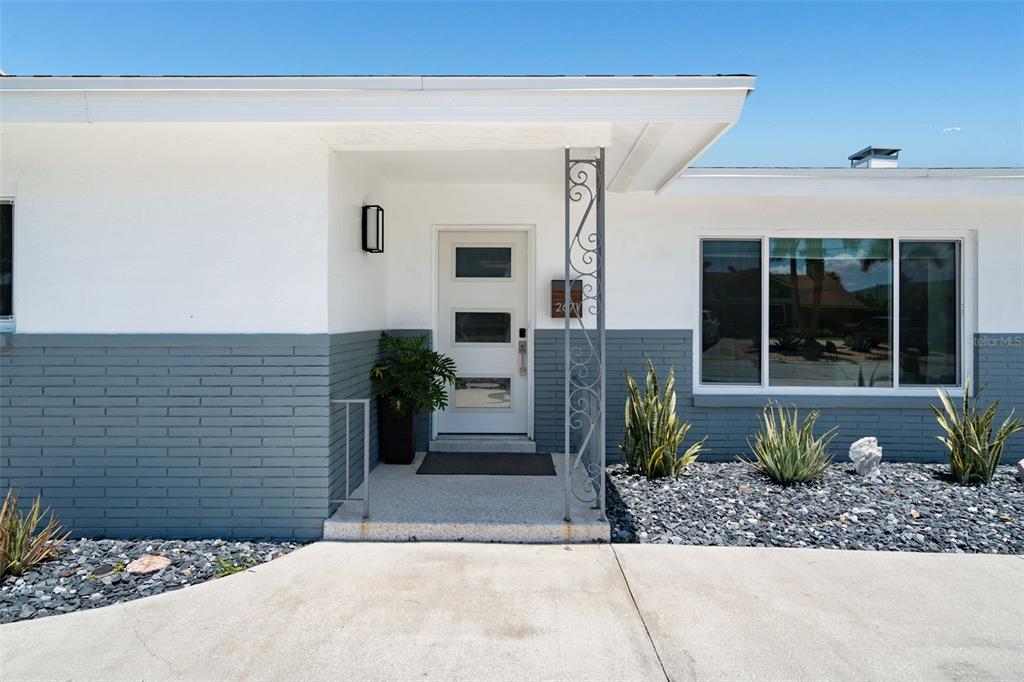 A living room features a green sofa, white armchairs, a glass coffee table, and terrazzo flooring — 2671 W BAY ISLE DRIVE SE, ST PETERSBURG, FL