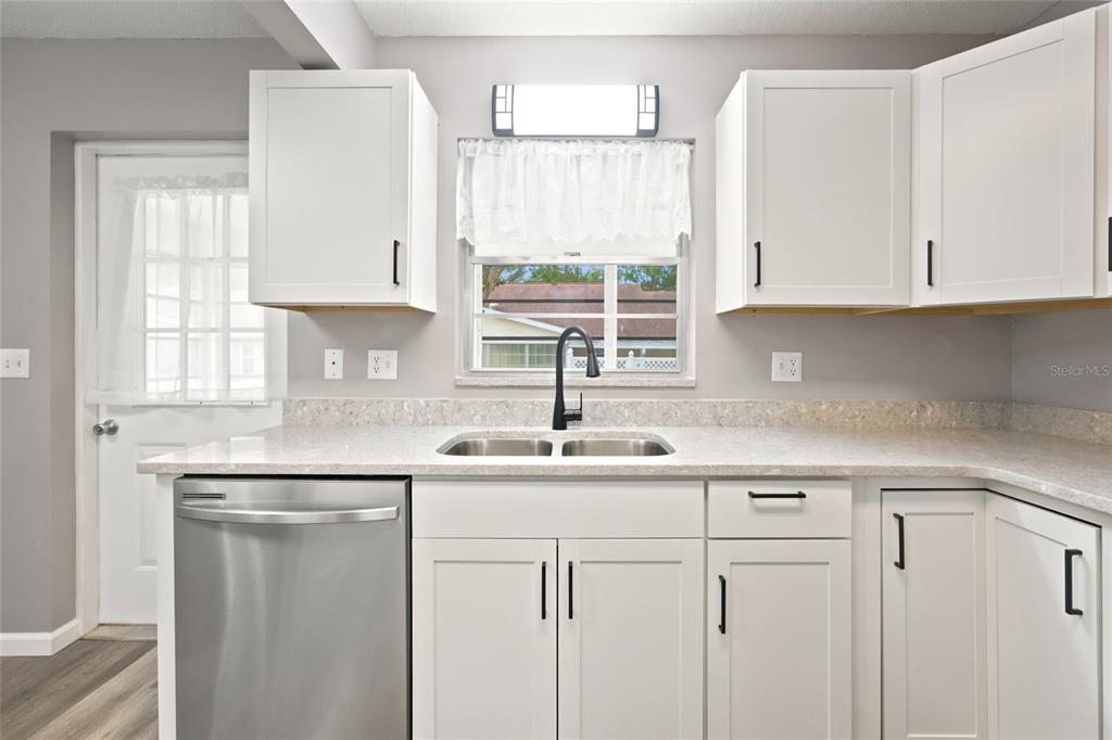 A kitchen features white cabinets, stainless steel appliances, a double sink, and a window — 8710 SW 96TH STREET UNIT C, OCALA, FL