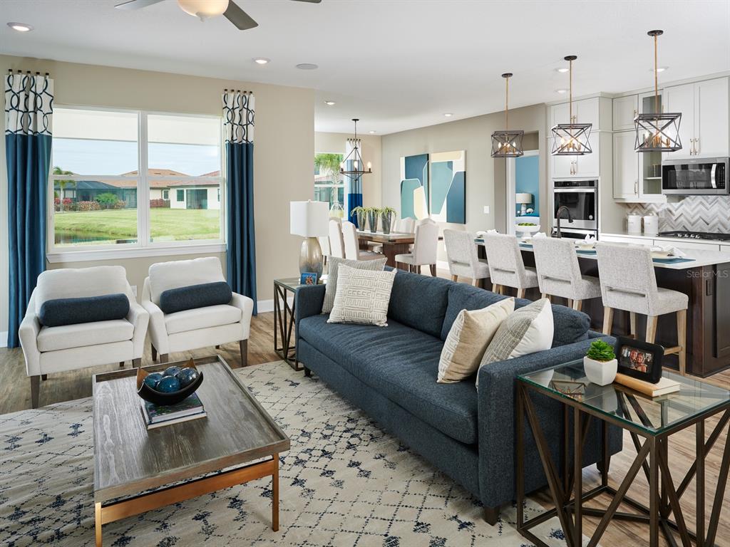 An open-concept living room and kitchen featuring a blue sofa, armchairs, and a dining area — 132 SUN CHASER DRIVE, NOKOMIS, FL