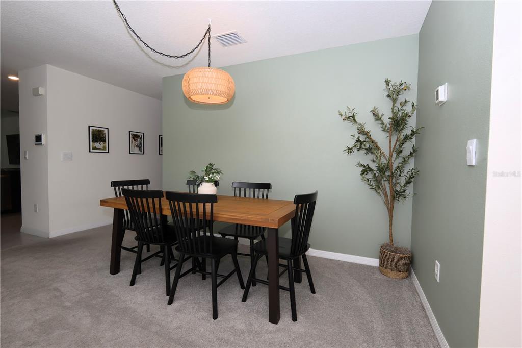 A dining area features a wooden table, black spindle chairs, and a sage green accent wall — 13726 WHISKEY DAISY DRIVE, DADE CITY, FL