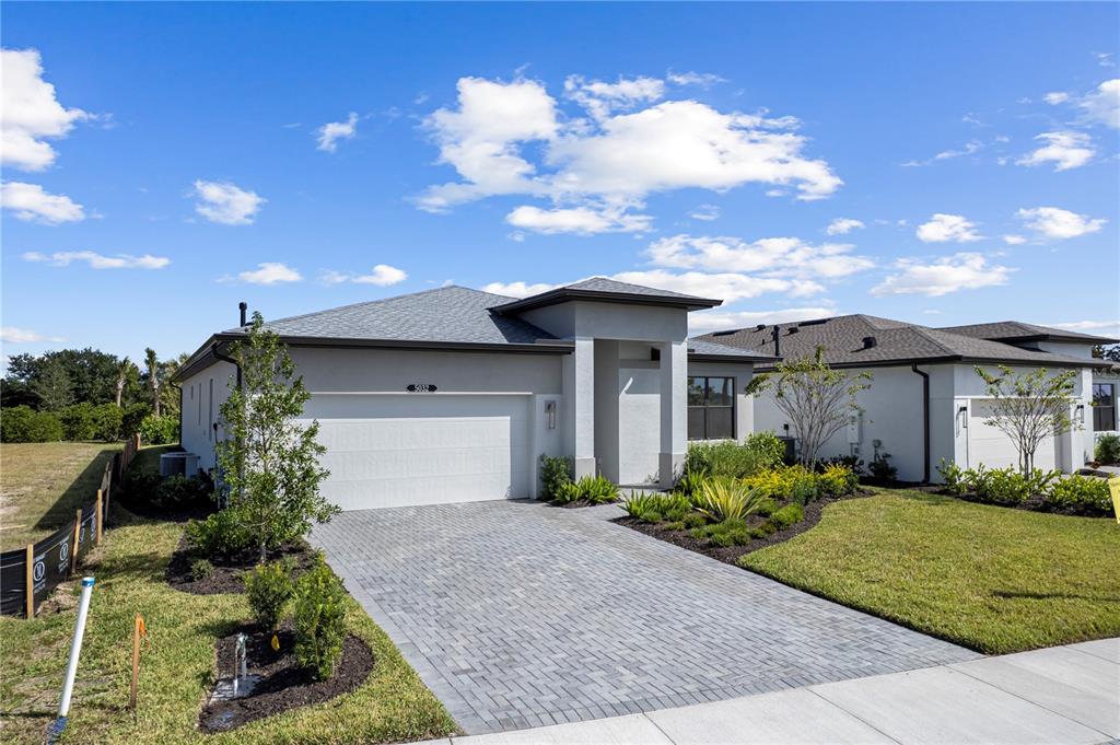 A single-story house with a white stucco exterior, a gray roof, and a paved driveway — 5032 LOWLAND TERRACE, PARRISH, FL