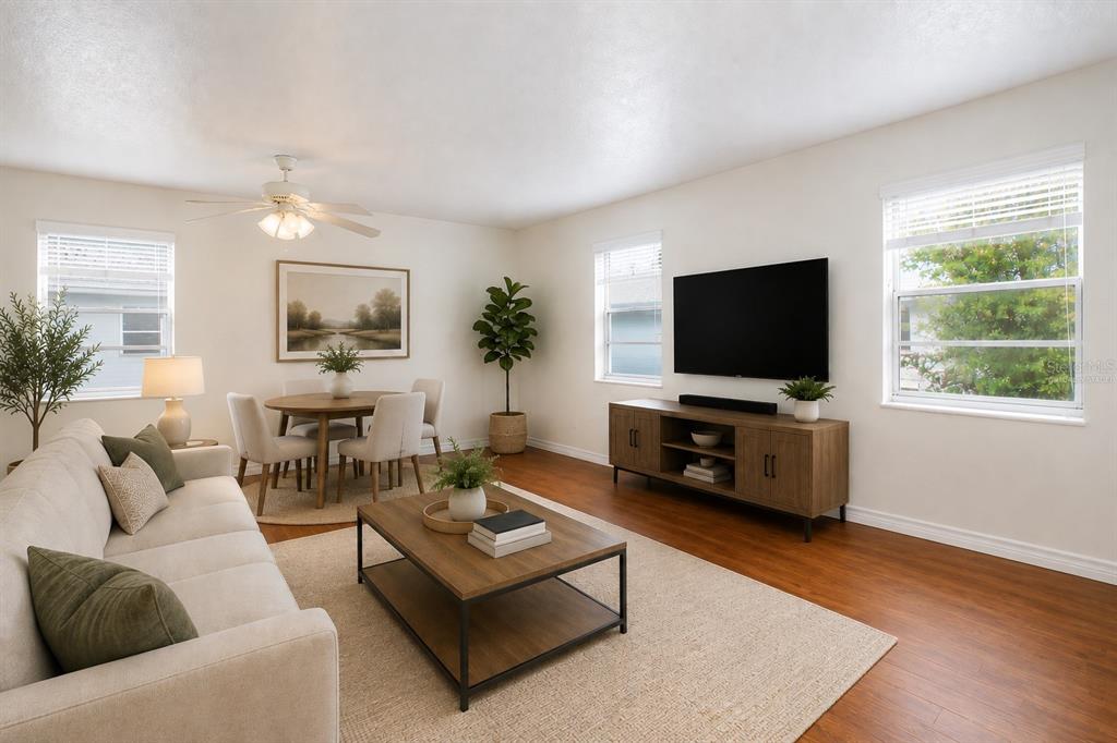 A living room with wood flooring, a beige sofa, a coffee table, and a television — 6940 A SUNSET DRIVE S UNIT 2C, ST PETERSBURG, FL