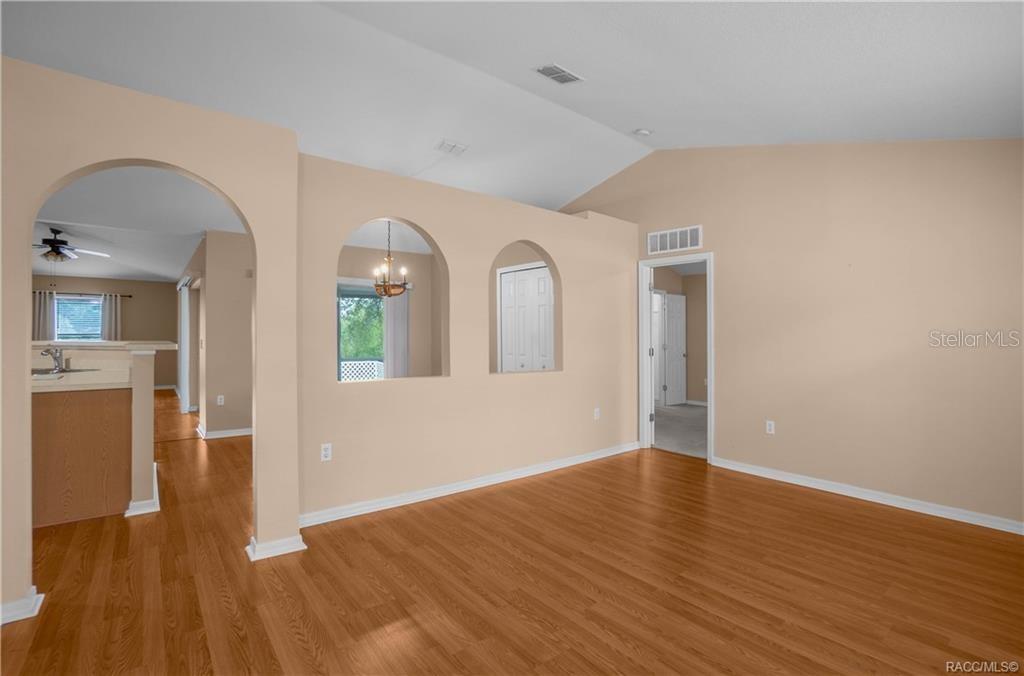 A living room with light-colored walls, wood-look flooring, and arched architectural cutouts — 3320 N BURROUGHS PATH, BEVERLY HILLS, FL
