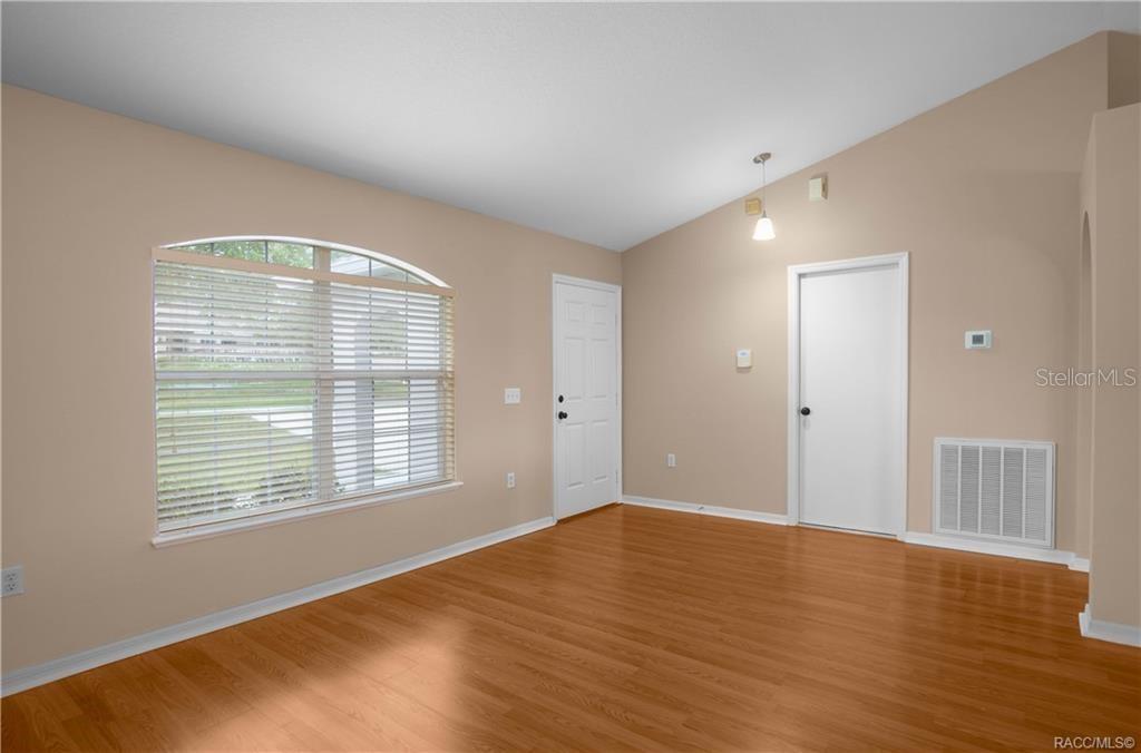 An empty room with light-colored walls, wood-look flooring, a large window, and two doors — 3320 N BURROUGHS PATH, BEVERLY HILLS, FL