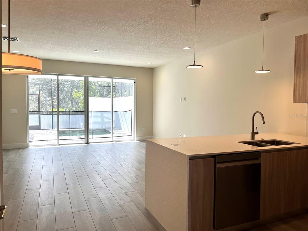 A modern kitchen with a large island overlooks a living area with sliding glass doors — 1427 SERENDIPITY LANE, CLERMONT, FL