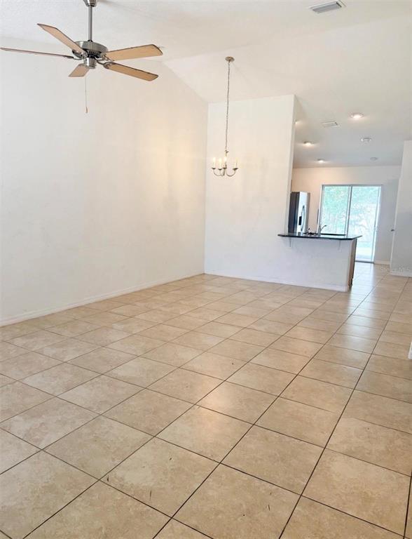 An open-concept living and dining area features light-colored tile flooring and a vaulted ceiling — 20 RAINSTONE LANE UNIT B, PALM COAST, FL