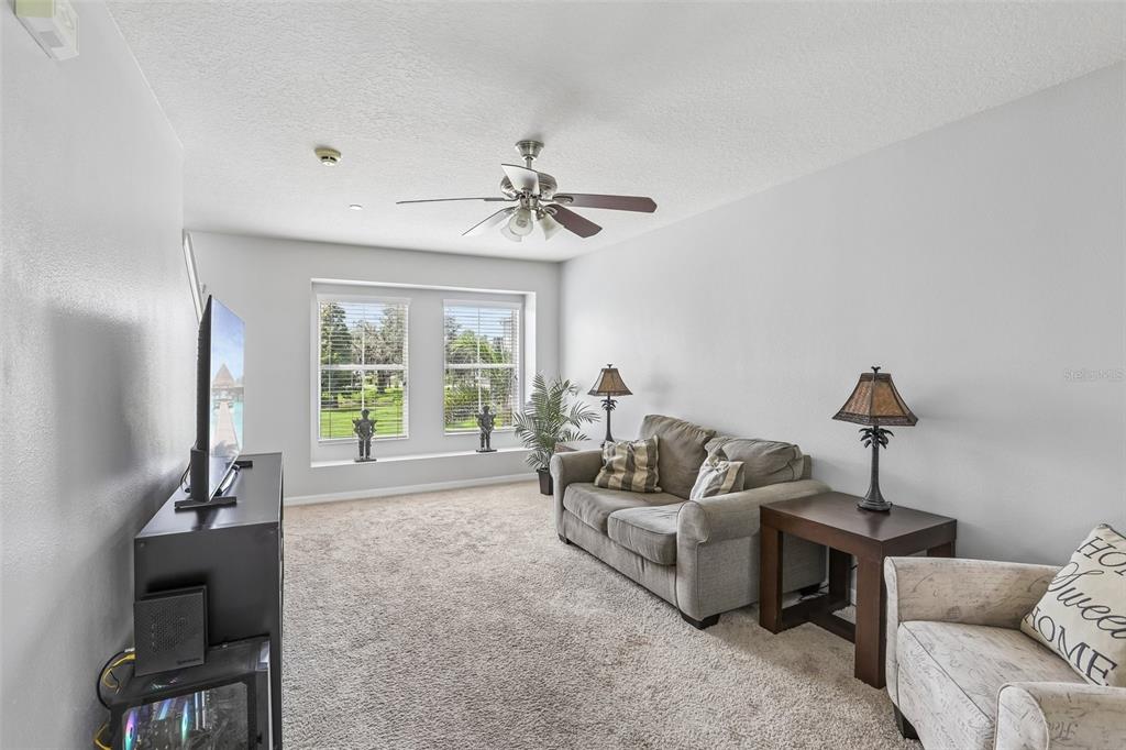 A kitchen features white cabinets, a center island, and an adjacent dining area with balcony access — 4864 TUSCAN LOON DRIVE, TAMPA, FL