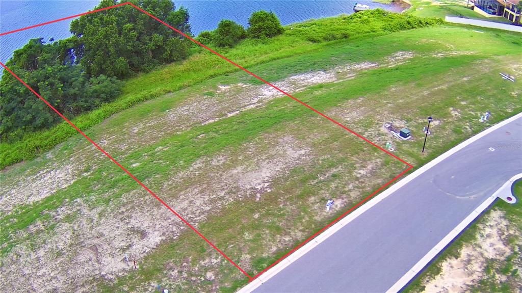 An aerial view shows a vacant, rectangular residential lot bordering a body of water — 4383 JULIANA LAKE DRIVE, AUBURNDALE, FL