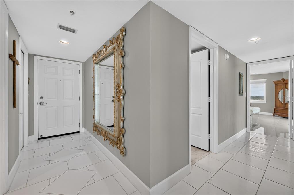 A white-tiled entryway features a large ornate gold mirror and a white front door — 2937 S ATLANTIC AVENUE UNIT 2002, DAYTONA BEACH SHORES, FL