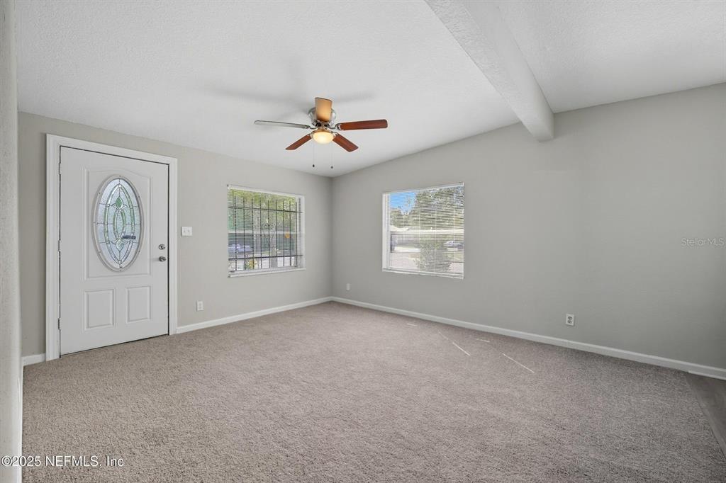 This living room features gray carpet, light gray walls, a ceiling fan, and a front door — 5306 PARIS AVENUE, JACKSONVILLE, FL