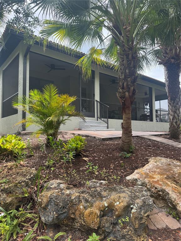 A screened-in porch with a patio and palm trees in a landscaped backyard — 408 TORTUGA DRIVE, NOKOMIS, FL