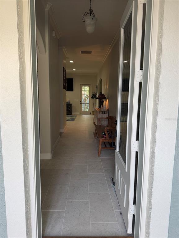 A view through an open front door into a tiled entryway hallway with a wooden bench — 408 TORTUGA DRIVE, NOKOMIS, FL