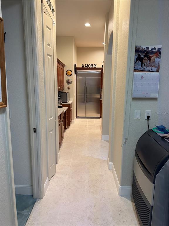 A hallway with light tile flooring leads to a kitchen featuring a stainless steel refrigerator — 408 TORTUGA DRIVE, NOKOMIS, FL