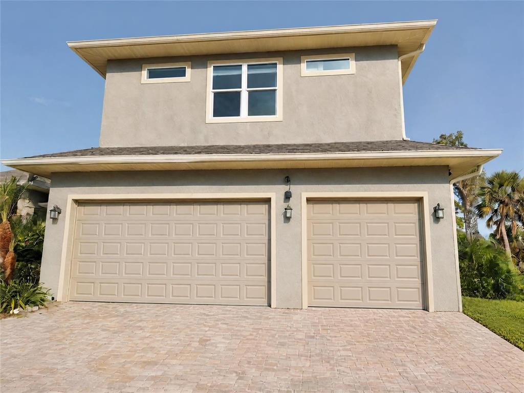 A two-story house exterior features a three-car garage, stucco siding, and a paved driveway — 935 LINDEN ROAD, VENICE, FL