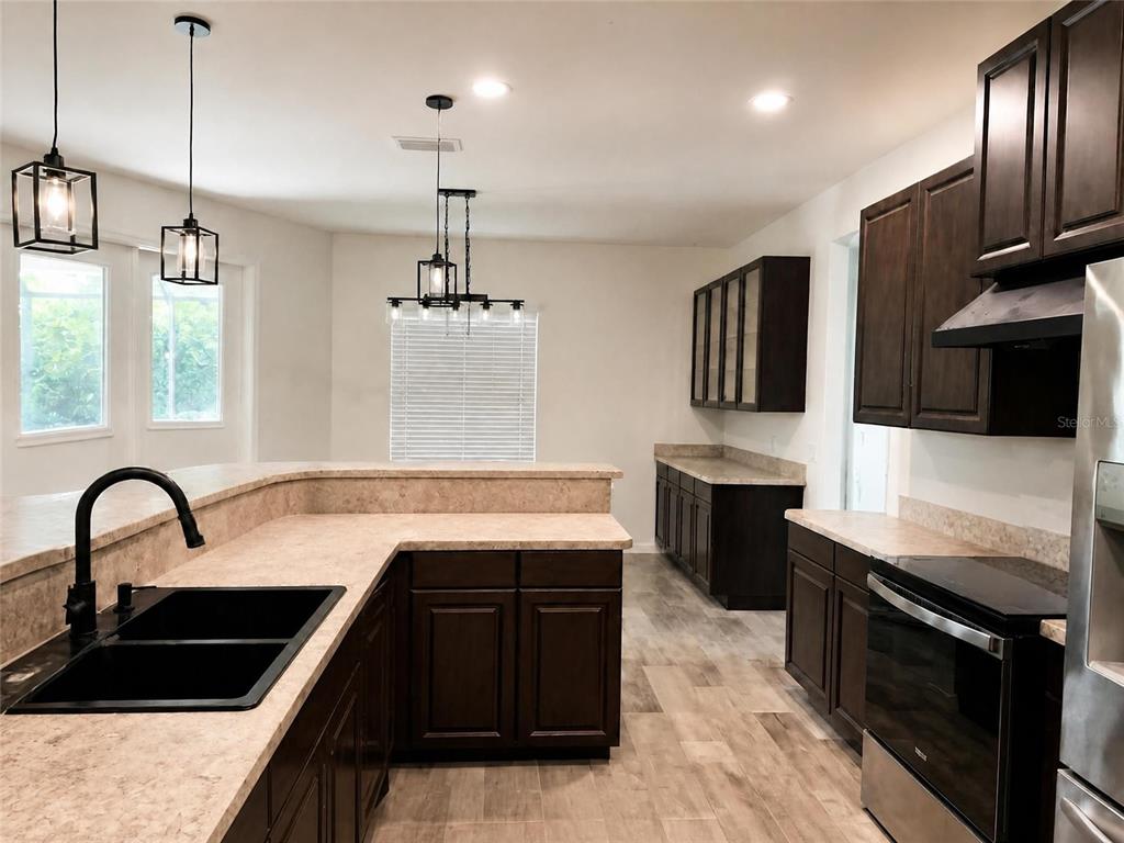 A kitchen features dark wood cabinets, light countertops, a black sink, and pendant lighting — 935 LINDEN ROAD, VENICE, FL
