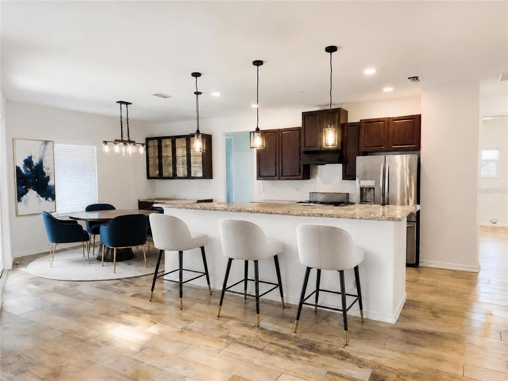 A kitchen and dining area features dark wood cabinets, granite countertops, and three bar stools — 935 LINDEN ROAD, VENICE, FL