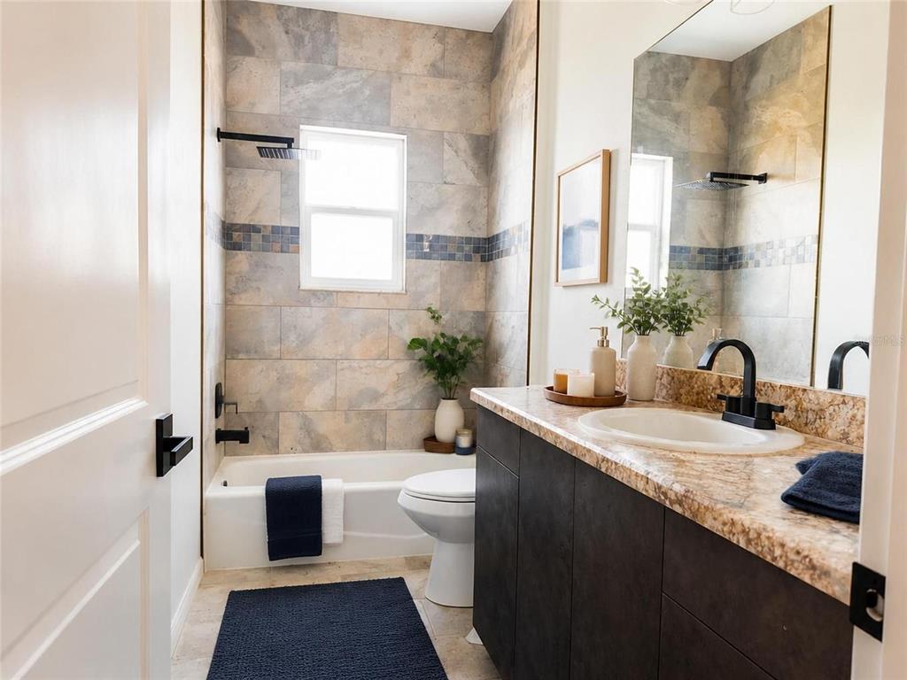 A bathroom features a tub-shower combo with stone tile, a dark vanity, and granite countertops — 935 LINDEN ROAD, VENICE, FL