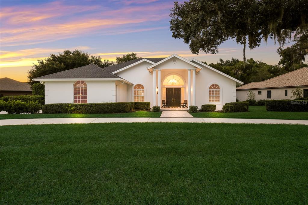 A white single-story house with a columned entryway and arched windows sits behind a lawn — 3649 WILDERNESS BOULEVARD W, PARRISH, FL