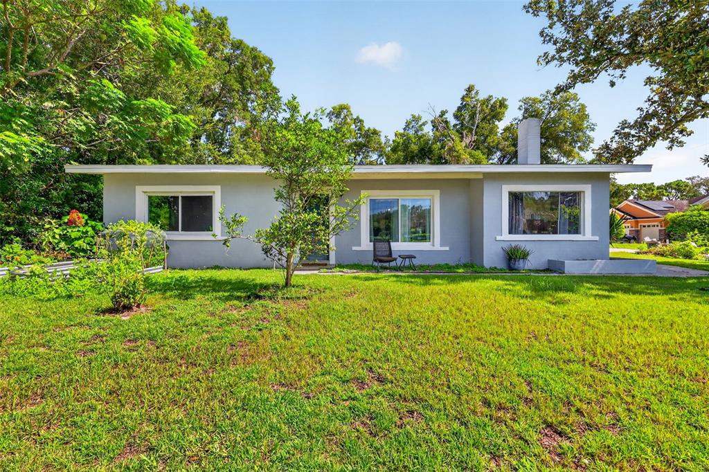 A single-story gray house with a flat roof sits on a grassy lawn with trees — 428 RUTH ST, LONGWOOD, FL