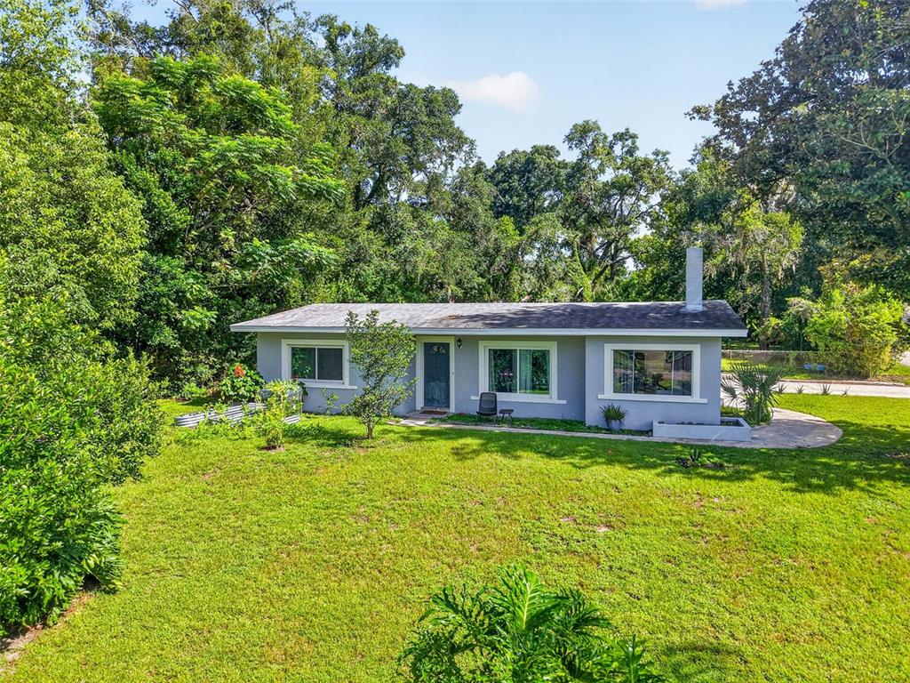 A single-story gray house with a white chimney sits on a grassy, tree-lined lot — 428 RUTH ST, LONGWOOD, FL